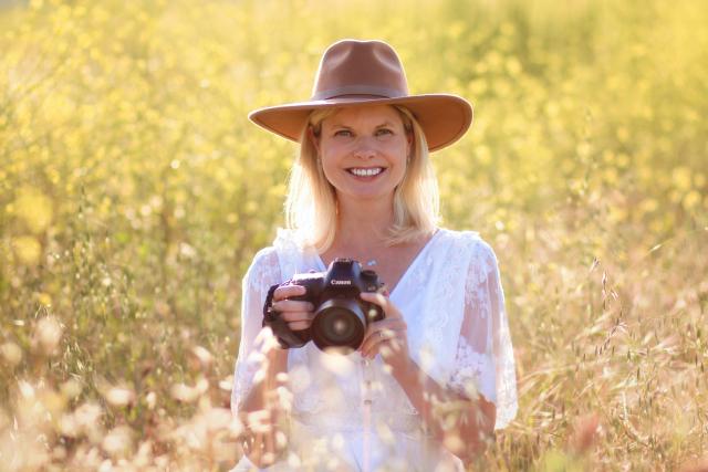 Photographer holding camera sitting in field