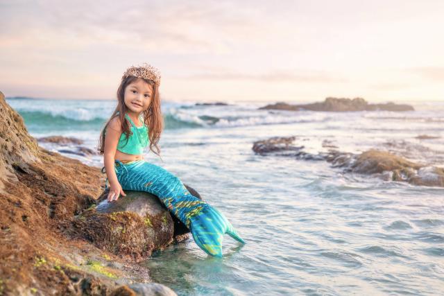 Little girl dressed as a mermaid on a rock